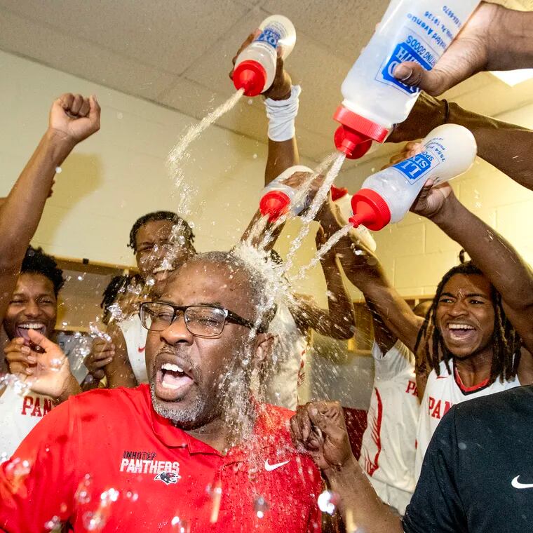 Coach Andre Noble of Imhotep Charter is doused with water in the locker room. after they defeated Math, Civics, & Sciences in the Philadelphia Boys Public League Championship at the Liacouras Center on Feb. 24, 2024.
