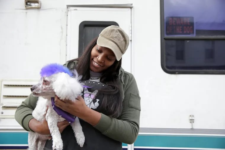 Rahanna Gray, owner of Stylish Pooch grooming, poses with Major next to her RV grooming business.