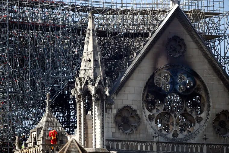 A fire fighter makes his way on a balcony of Notre Dame cathedral Wednesday, April 17, 2019 in Paris. French President Emmanuel Macron ratcheted up the pressure by setting a five-year deadline to restore the 12th-century landmark.