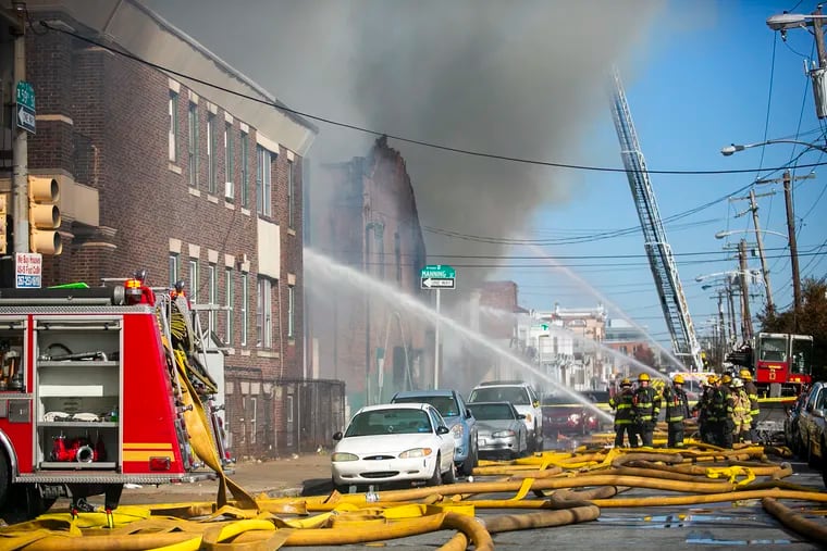Fire crews battle a three-alarm fire at a garage in West Philadelphia on Monday.
