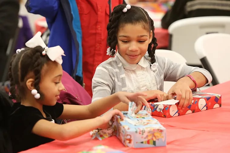 Jazlyn Carter (right), 7, of Atlantic City, and her sister Amery, 6, open presents during the Just 4 Kids Foundation's annual toy giveaway at St. Michael's Church in Atlantic City on Saturday, December 20, 2014.