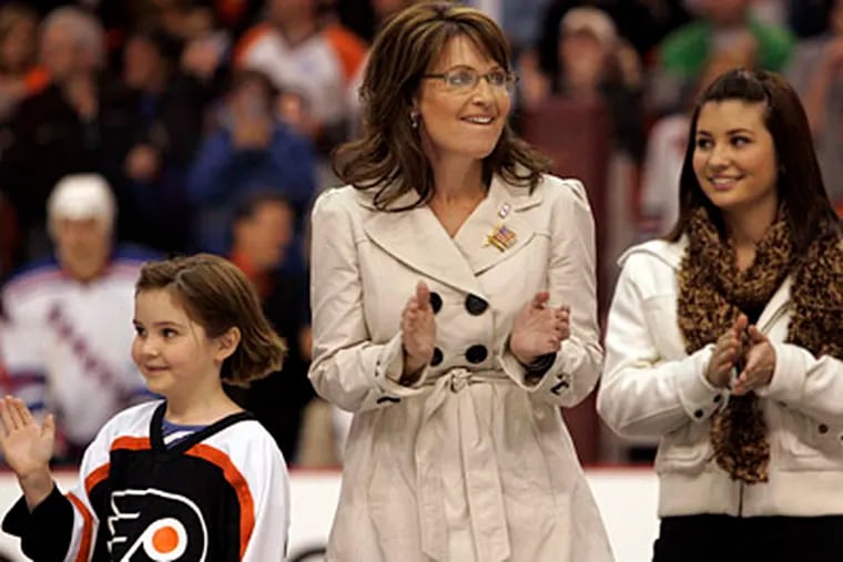 Sarah Palin, and daughters Piper (left) and Willow, wave to the crowd in the Wachovia Center as she walks on to the ice to drop the first puck of the Flyers' season.  (Laurence Kesterson / Inquirer)