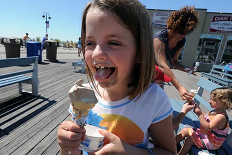 Gracyn Shaw, 6, of Ardmore, enjoys ice cream as her mother, Jenn, assists sister Porter, 2, in the background at Ocean City. The hurricane evacuation interrupted what was so far a good season for Shore businesses. (Sharon Gekoski-Kimmel / Staff Photographer)
