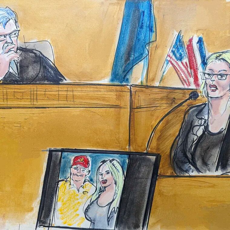 In this courtroom sketch, Stormy Daniels testifies on the witness stand as Judge Juan Merchan looks on in Manhattan criminal court Tuesday. A photo of Donald Trump and Daniels from their first meeting is displayed on a monitor.