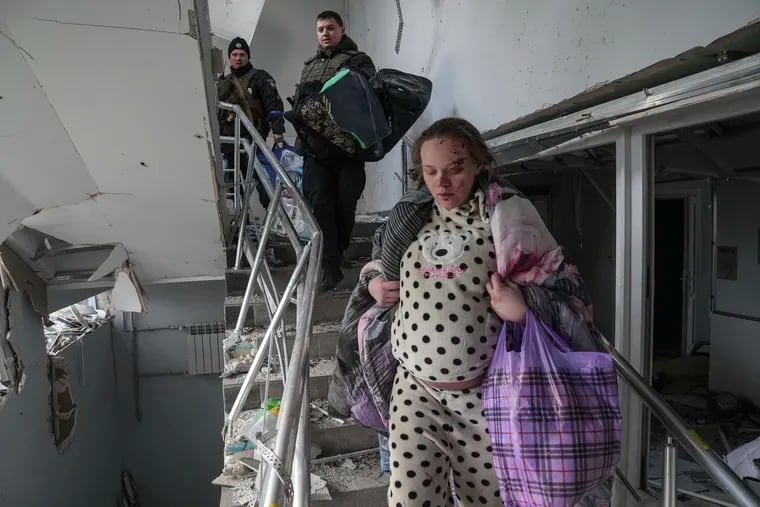 An injured pregnant woman walks downstairs in the maternity hospital in Mariupol, Ukraine, after it was damaged by Russian shelling on March 9.