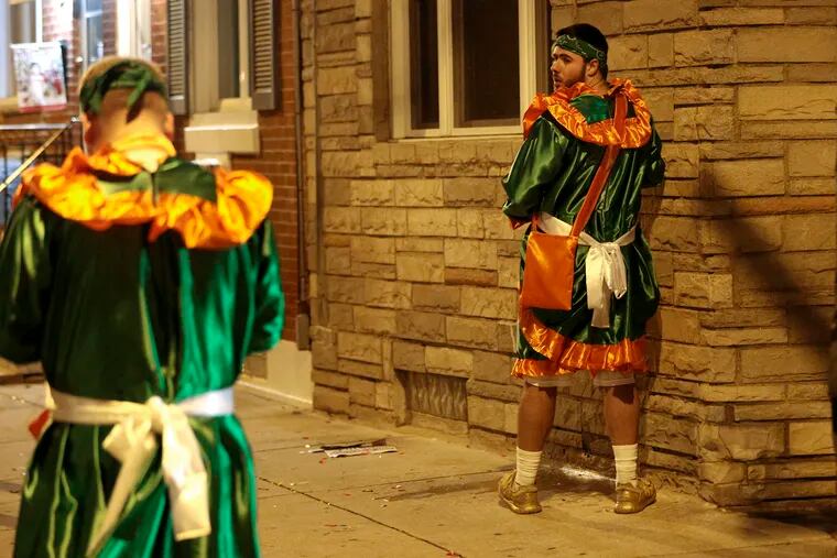 A Mummer pees on a house just off of Second Street after the Mummers Parade in Philadelphia on Jan. 2, 2022.
