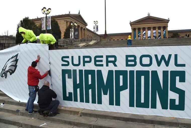 Workers attach a huge banner to the front of the stage at the Philadelphia Museum of Art as preparations continue for Thursday’s Eagles Super Bowl victory parade.