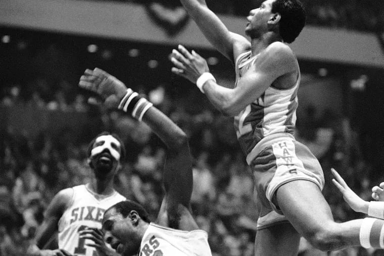 Atlanta Hawks' John Drew soars towards basket and knocks Sixers' Darryl Dawkins to the floor, April 9, 1980 in NBA playoff game at Philadelphia. Drew's basket did not count and a foul was charged. Sixers Caldwell Jones is in background. Of course, there was a foul on the play.