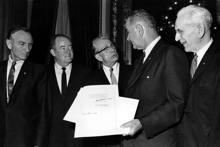 President Lyndon Johnson holds the signed document of the Voting Rights Act of 1965. From left, Sen. Mike Mansfield, Vice President Hubert Humphrey, Sen. Everett Dirksen, and House Speaker John McCormack flank Johnson.