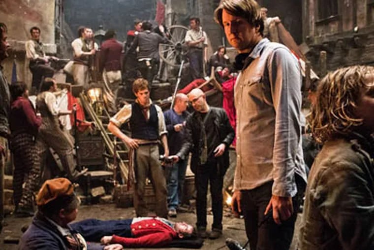 This undated publicity photo provided by Universal Pictures shows OscarÆ-winning director, Tom Hooper, center, and Daniel Huttlestone, right, as Gavroche on the set of Hooper's new film, "Les MisÈrables," the motion-picture adaptation of the beloved global stage musical adapted from Victor Hugoís novel. (AP Photo/Universal Pictures/James Fisher)