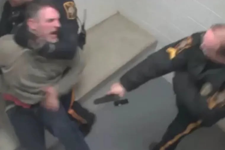A screenshot from a surveillance video shows New Hope police officer Matthew Zimmerman (right) shooting Brian Riling in the stomach while in a holding cell.