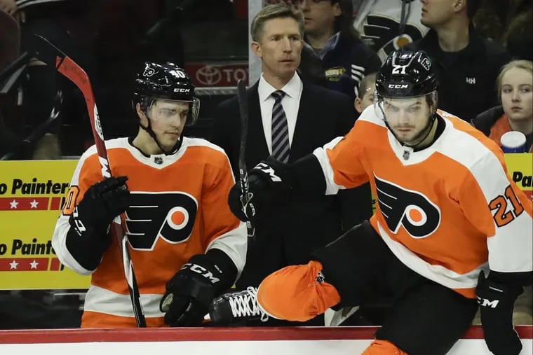 Flyers coach Dave Hakstol watches his team next to center Travis Konecny and center Scott Laughton leaping on the ice against the St. Louis Blues on Saturday, January 6, 2018 in Philadelphia.