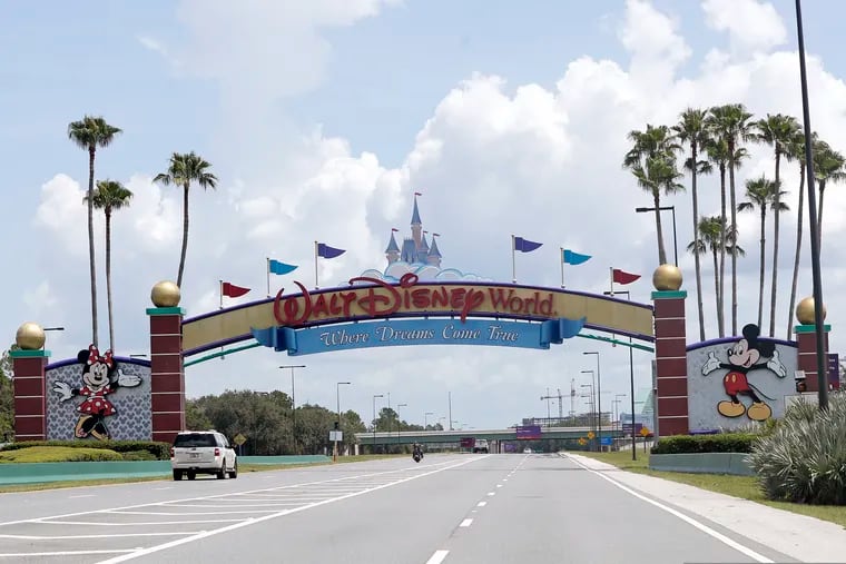 Cars drive under a sign greeting visitors near the entrance to Walt Disney World.