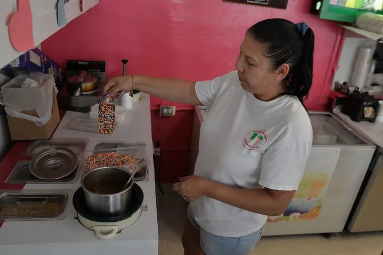 Noelia Scharon dips this ice cream bar in melted chocolate then coats it in sprinkles. Thirty flavors of both traditional and exotic ice creams  are available at La Michoacana Ice Cream in Kennett Square on July 12h, 2019 (Photo by Bob Williams For The Inquirer)