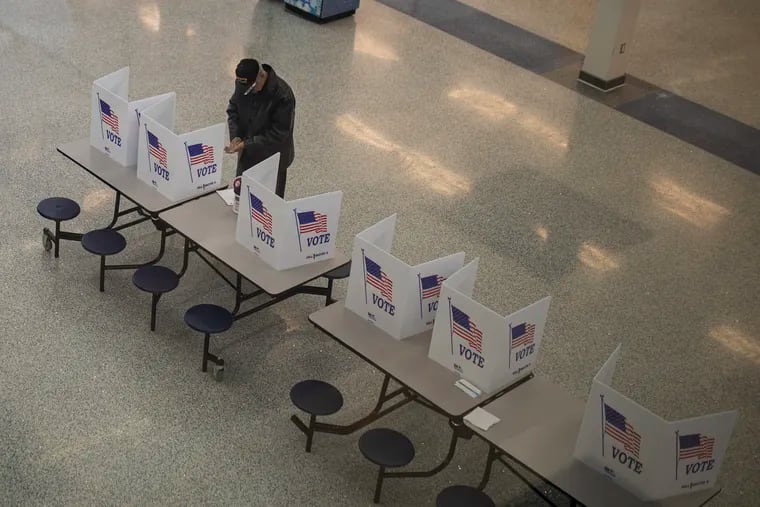 A man cleans his hands before filling out his ballot to vote at Bensalem High School in a special election for a Bucks County state House seat on March 17, 2020.