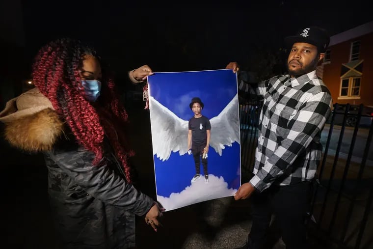 Calina Brown, left, and Darius Callicut, right, hold a photograph of their cousin Samir Jefferson at a vigil that took place at Harrity Elementary School in Philadelphia, Dec. 2, 2021.