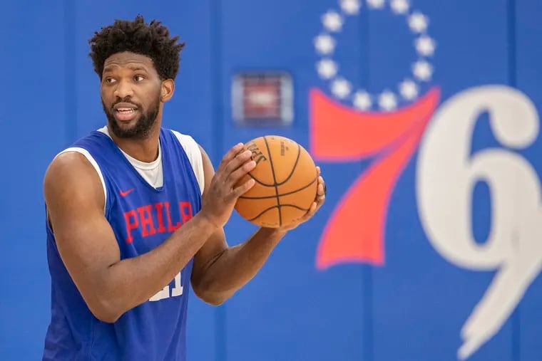 Sixer center Joel Embiid looks to a teammate during shooting drills at practice at the Sixers facility, in Camden, NJ, in February.