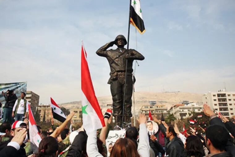 Pro-regime demonstrators rally around a statue of a soldier at Umayyad Square in Damascus. Syrian troops reportedly surrounded a valley Tuesday and killed 110 people. (Bassem Tellawi / Associated Press)