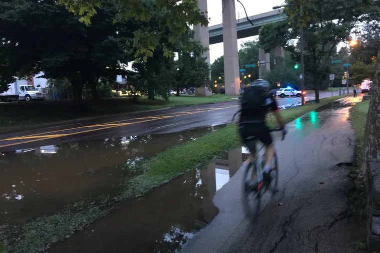 Cyclist rides along Kelly Drive early Tuesday morning after floodwaters receded along the Schuylkill.