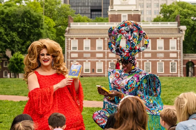 Drag queens Brittany Lynn (left) and Morgan Wells read “Giraffes Can’t Dance" to children in front of Independence Hall in a new Pride Month public service announcement encouraging LGBTQ+ travelers to book a trip to the city.