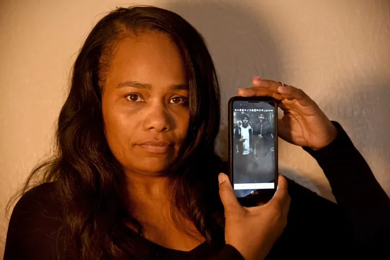 Maria Yelverton, whose two sons were killed outside a cousin's house in East Mount Airy last month, shows a cellphone photo of them (Raheem Martin, 24, left, and Samir Yelverton, 23). No one has been arrested in the slayings.