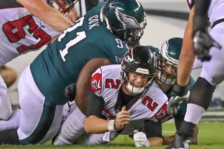 Atlanta's Matt Ryan,center, is thrown to the ground by Eagles defensive tackle Fletcher Cox, left, in the fourth quarter and forced him to fumble the ball, it was recovered by the Falcons. The Philadelphia Eagles host the Atlanta Falcons in their home opener on September 6, 2018. MICHAEL BRYANT / Staff Photographer