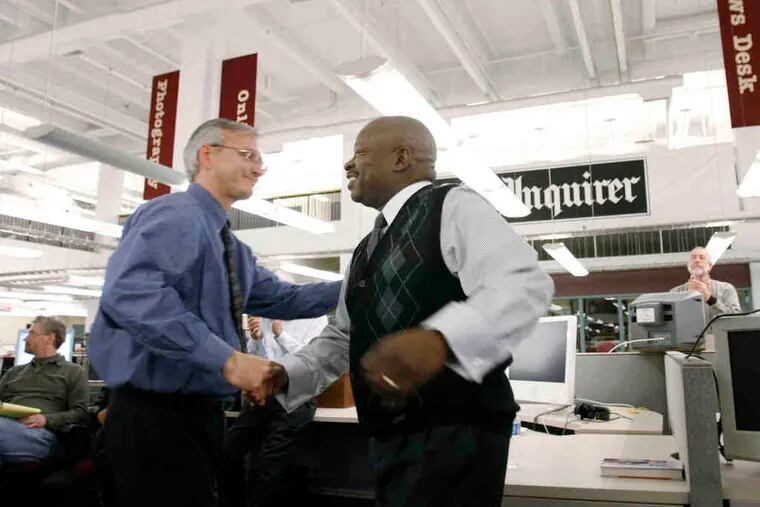 Michael Days (right) is congratulated by Inquirer editor Stan Wischnowski after the announcement in the Inquirer newsroom. &quot;We realized we shared a passion for journalistic excellence,&quot; said Days, a city native.
