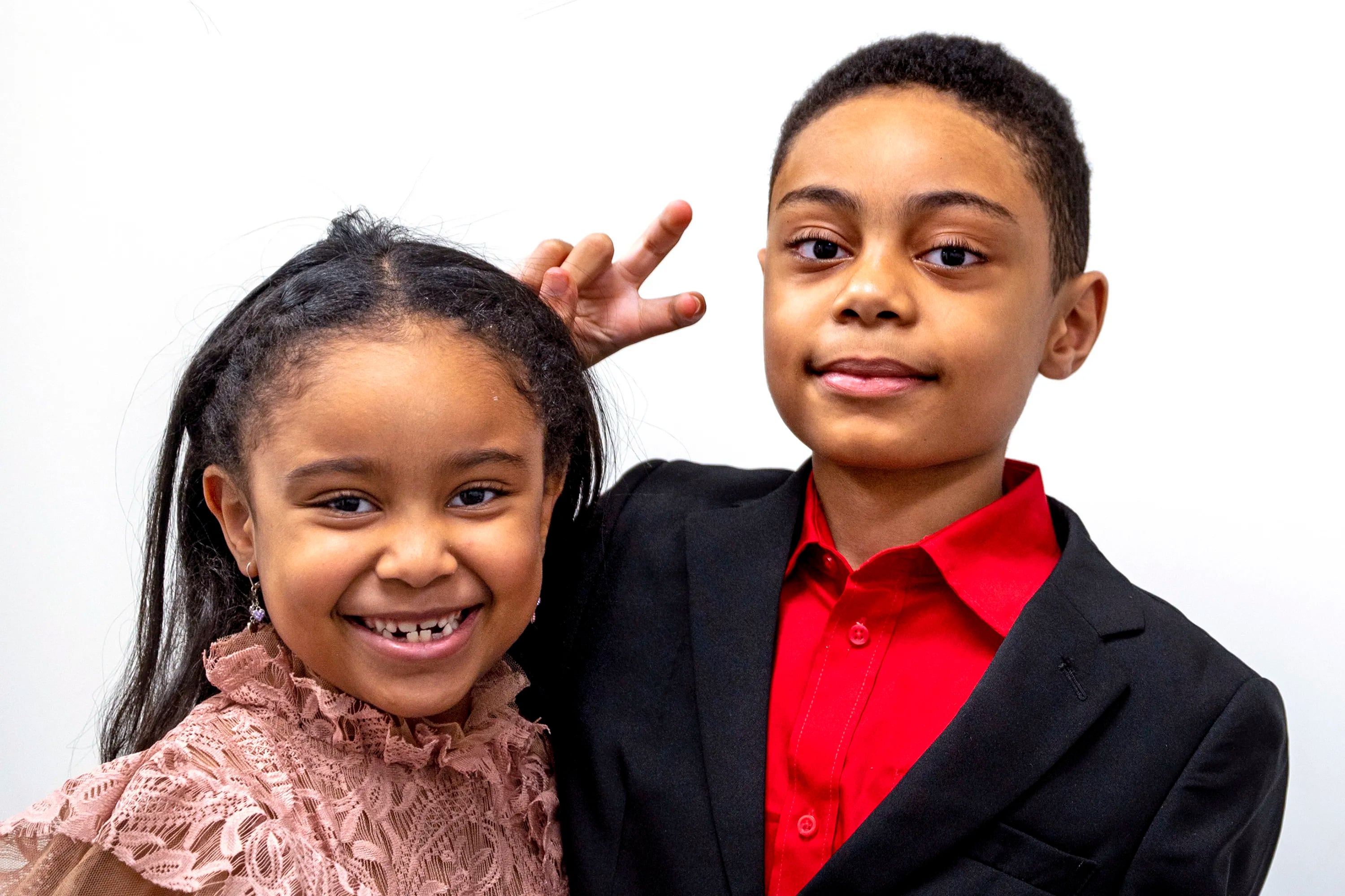 David Balogun gives his sister Eliana, 6, bunny ears while they pose for a photo at their father’s office. David, who just graduated from high school, one of the youngest people ever to do so, is into black holes and space theory and is contemplating where he'll attend college.