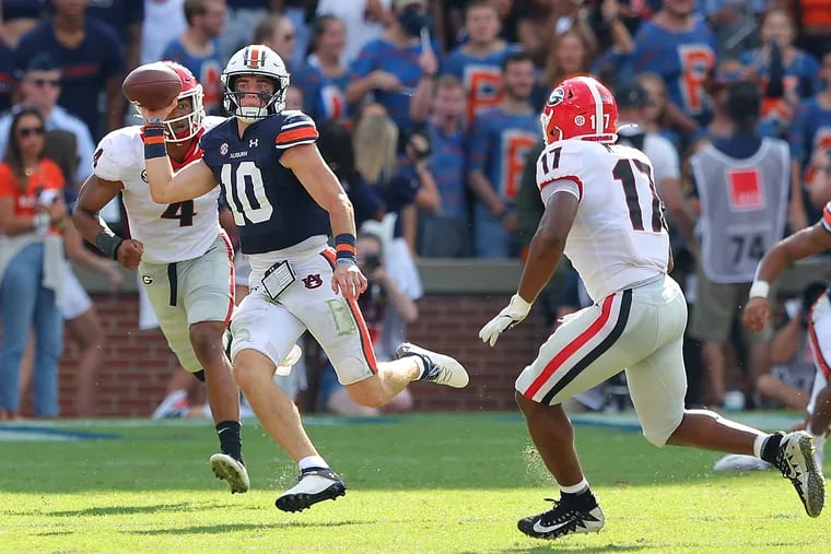 Bo Nix #10 of the Auburn Tigers rushes against Nolan Smith #4 and Nakobe Dean #17 of the Georgia Bulldogs during the first half at Jordan-Hare Stadium on October 09, 2021 in Auburn, Alabama.