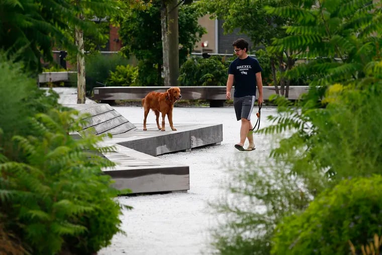 Santiago Uribe and his Golden Retriever Koda take a walk along the Rail Park on Thursday, July 18, 2019. Opponents of the Callowhill BID thought it was a way to fund maintenance of the park.