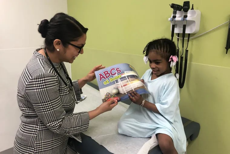 Hera Mahmood gives Aubrey Brown, 4, a book.