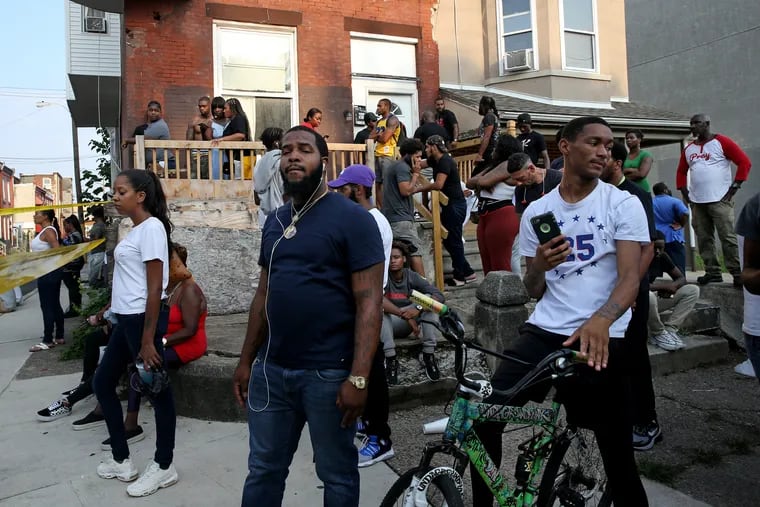 Neighborhood residents and onlookers gather along 15th Street south of Erie Avenue August 14, 2019, where six police officers were shot in a confrontation with a gunman in the Tioga section of North Philadelphia.