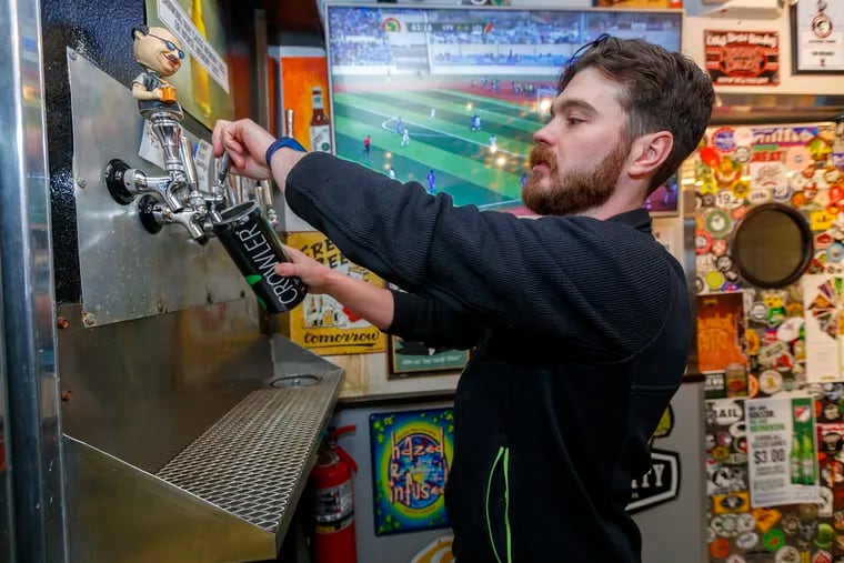 At Pinocchio's Beer Garden to Go, Jason Mowery, the assistant manager, pours a crowler from one of the taps they have for craft beer, on March 25, 2019.