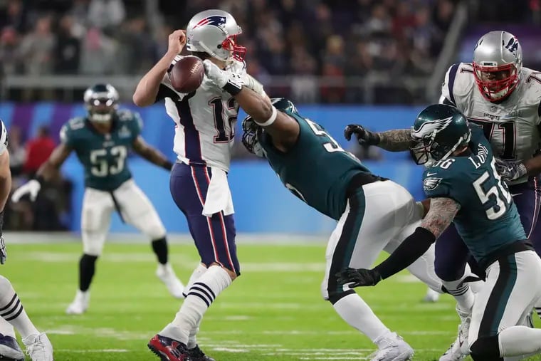 In a huge fourth-quarter play, Brandon Graham knocks the ball out of Tom Brady's hand as defensive end Chris Long moves in. Derek Barnett recovered the fumble, and the Eagles went on to win Super Bowl LII.