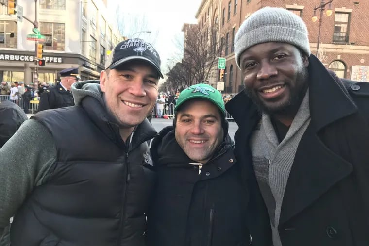 David Rankin and Eric Workman, Eagles fans from Lower Merion, Pa. (left to right), wait for the Super Bowl Parade at Broad and Pine Streets alongside former Eagles linebacker Moise Fokou on Thursday, Feb. 8, 2018.
