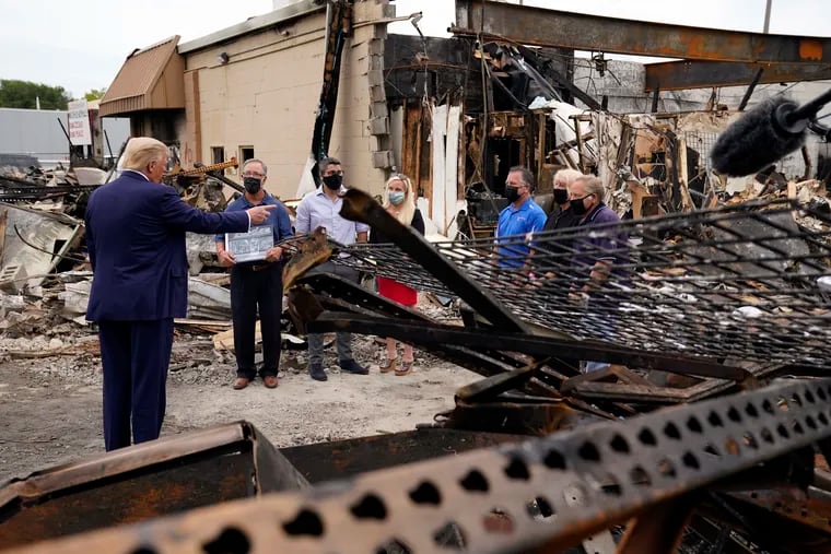 President Trump (left) talks to business owners Tuesday as he tours an area damaged during demonstrations after a police officer shot Jacob Blake in Kenosha, Wis.