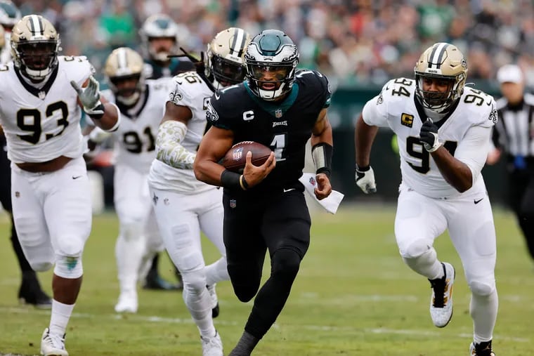 Eagles quarterback Jalen Hurts (1) is chased by New Orleans defenders during Sunday's game.