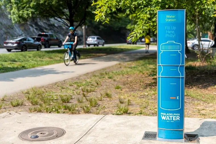 One of the blue water fountains stationed along Kelly Drive as a biker passes by in Philadelphia on Tuesday.