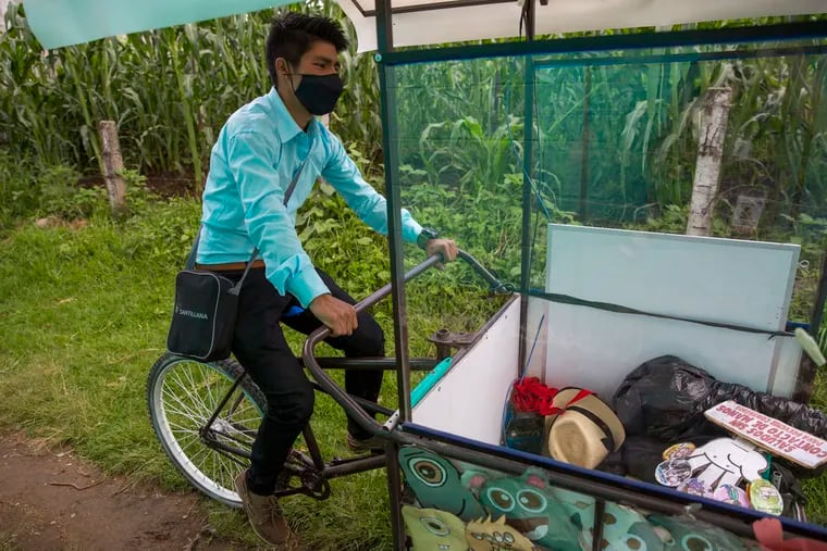 Teacher Gerardo Ixcoy pedals his adult tricycle converted into a mobile classroom past cornfields in Santa Cruz del Quiche, Guatemala. When the novel coronavirus closed Guatemala's schools in mid-March, the 27-year-old invested his savings in the classroom-on-a-trike in order to give individual instruction to his sixth-grade students. (AP Photo/Moises Castillo)