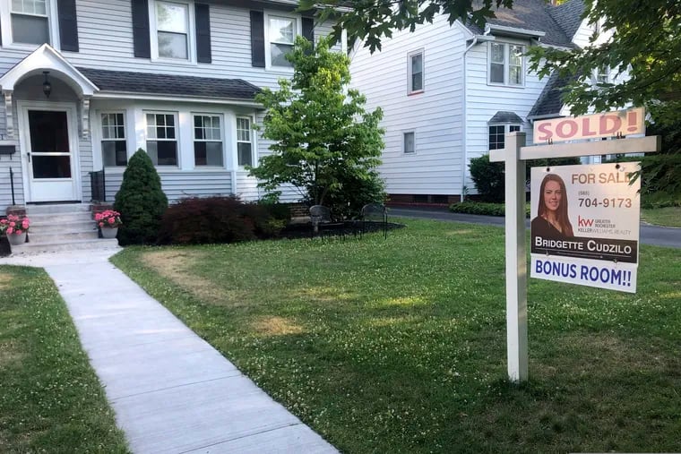 A sold sign hangs in front of a house in Brighton, N.Y. Long-term U.S. mortgage rates fell the first week of July with the benchmark 30-year home loan hitting its lowest level ever.