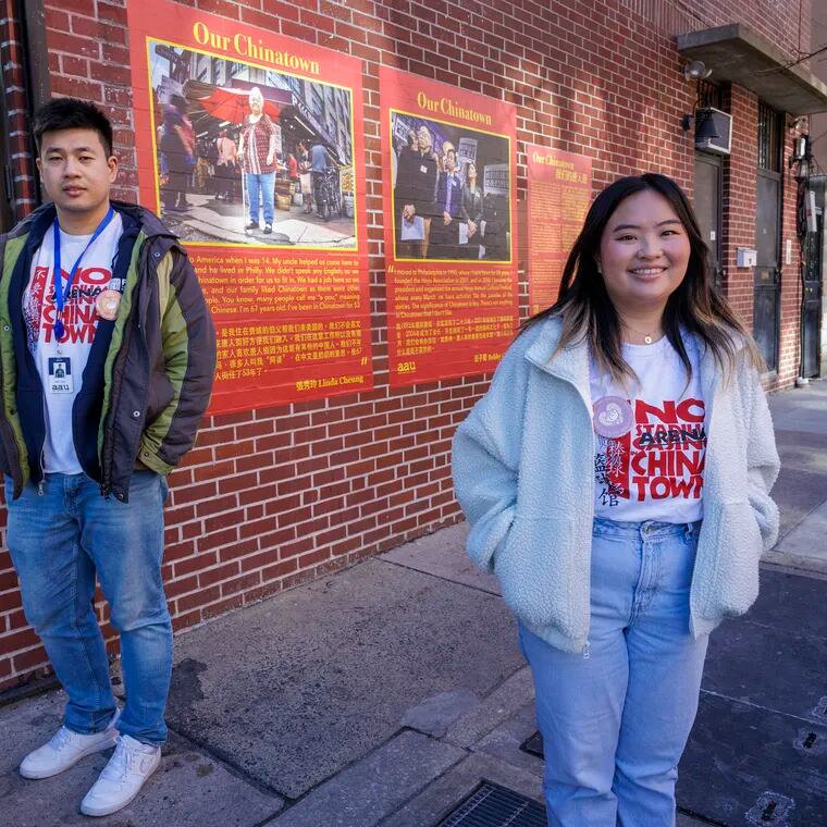 Wei Chen (left) and Cinthya Hioe of Asian Americans United stand in front of portraits of community members from the Chinatown community on display at Spring Street at N. 10th, as part of the "Our Chinatown" oral history project, Monday, Feb. 19, 2024.