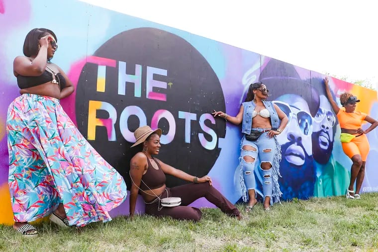 Festival-goers pose in front of a mural of Questlove and Black Thought at last year's Roots Picnic at the Mann Center. The festival will return to the Mann on June 1 and 2.