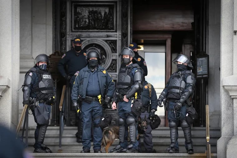 Pennsylvania Capitol Police officers, in riot gear, gather on the steps of the Harrisburg Capitol complex in Harrisburg on Sunday.