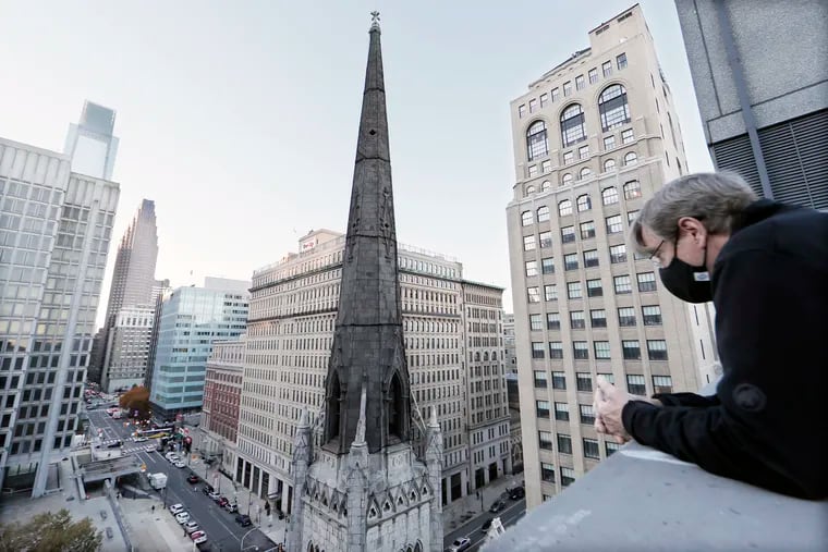 From the top floor of an adjacent parking garage, Arch Street United Methodist Church Pastor Robin Hynicka looks over the church and the protective netting covering its steeple on Nov. 12, 2021. The historic Philadelphia church is launching a major renovation effort to stabilize its steeple, which the city has declared unsafe.