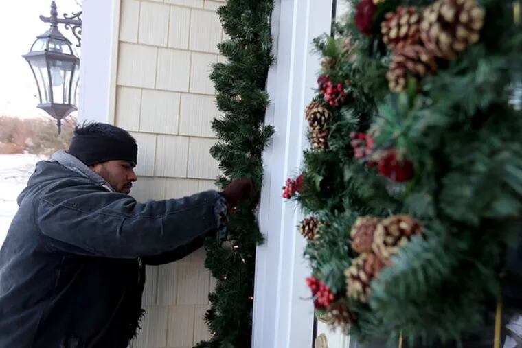 Antelmo Gonzales, of Michigan Holiday Lighting, puts the finishing touches on holiday decorations on a 3,500 square foot home in Clarkston, Mich., Dec. 11, 2013. (Andre J. Jackson/Detroit Free Press/MCT)