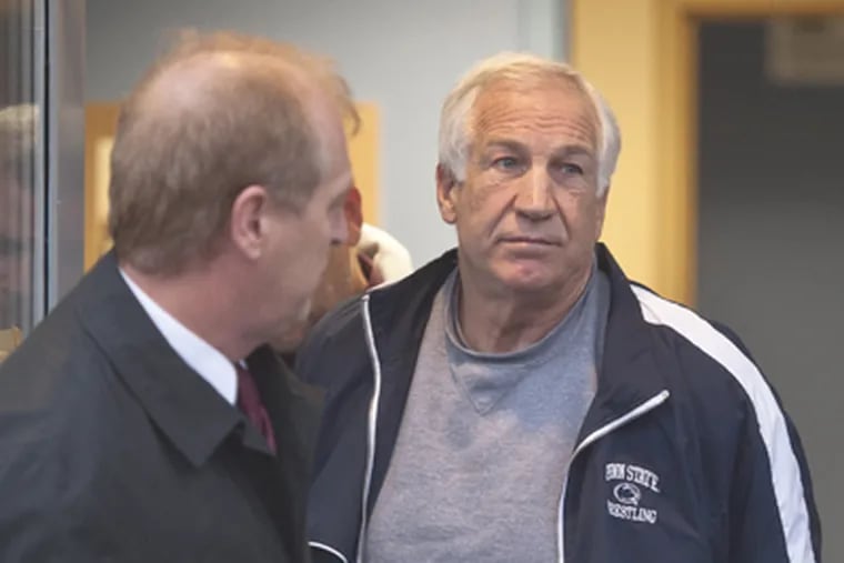 Former Penn State assistant football coach Jerry Sandusky, right,
leaves the office of Centre County District Justice Daniel A. Hoffman
under escort by Pennsylvania State Police and Attorney General's
Office officials in Bellefonte, Pa. (AP Photo/The Patriot-News, Andy Colwell)