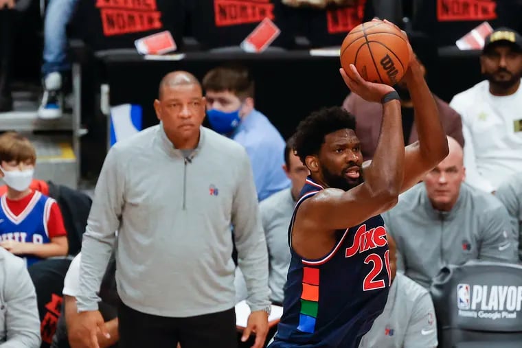 Sixers center Joel Embiid shoots the basketball with coach Doc Rivers watching against the Toronto Raptors during game four of the first-round Eastern Conference playoffs on Saturday.