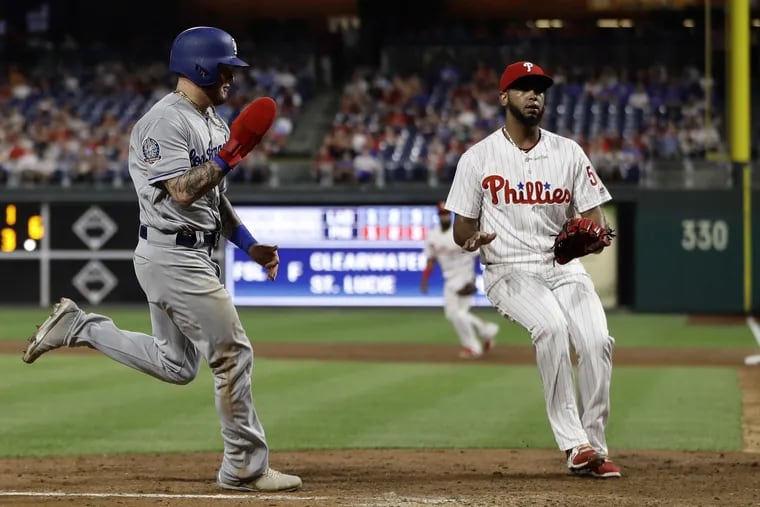 Los Angeles Dodgers' Alex Verdugo, left, scores past Philadelphia Phillies relief pitcher Seranthony Dominguez on a wild pitch during the ninth inning of a baseball game, Monday, July 23, 2018, in Philadelphia. Los Angeles won 7-6. (AP Photo/Matt Slocum)
