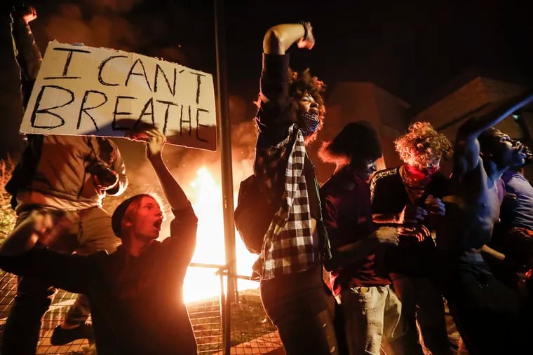 Protestors demonstrate outside of a burning Minneapolis 3rd Police Precinct on Thursday in Minneapolis. Protests over the death of George Floyd, a black man who died in police custody Monday, broke out in Minneapolis for a third straight night.