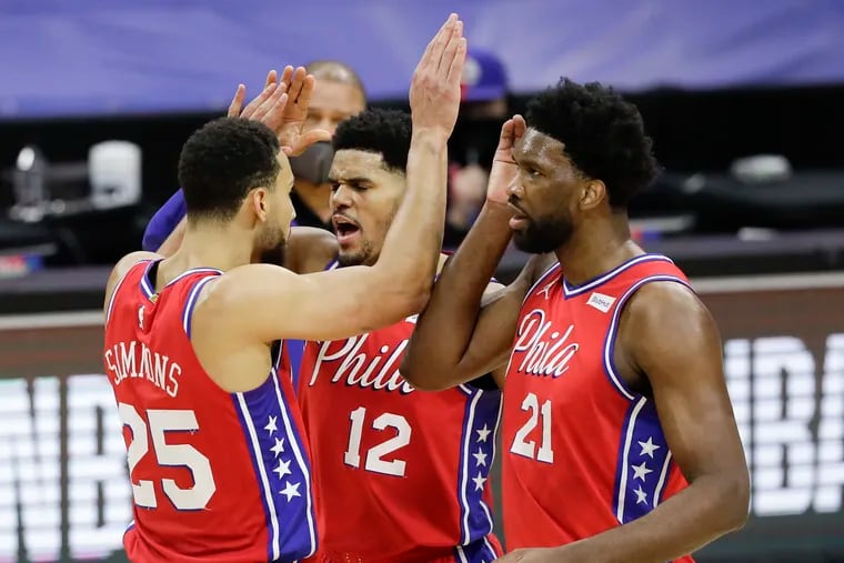 Sixers guard Ben Simmons, forward Tobias Harris and center Joel Embiid high five each other against the Boston Celtics on Friday.